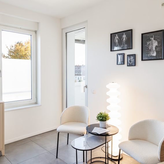 Heller Sitzecke mit zwei Stühlen, Tisch, Lampe und Bildern an der Wand.