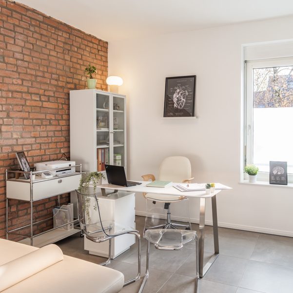 Heller Besprechungsraum mit Ziegelwand, Schreibtisch und modernem Mobiliar.